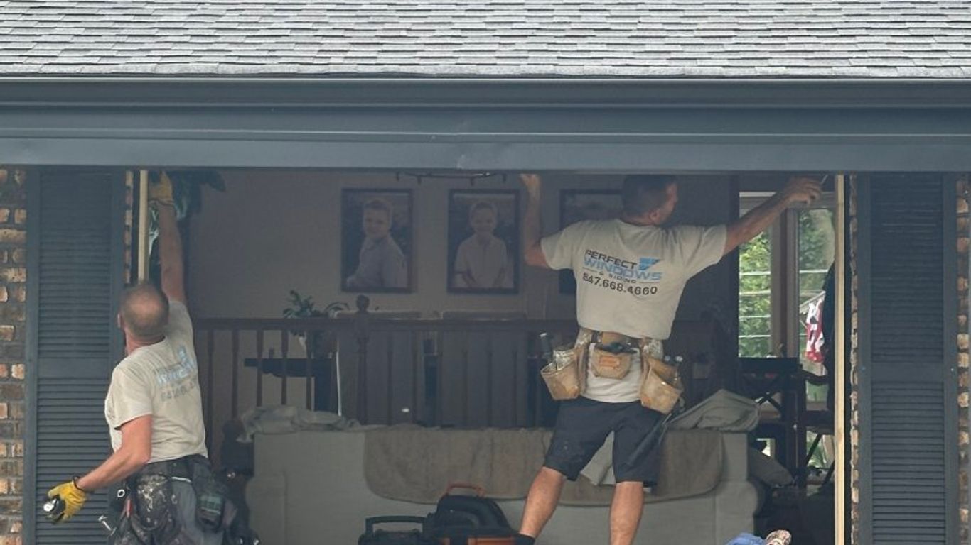 Workers installing a window in a house exterior.
