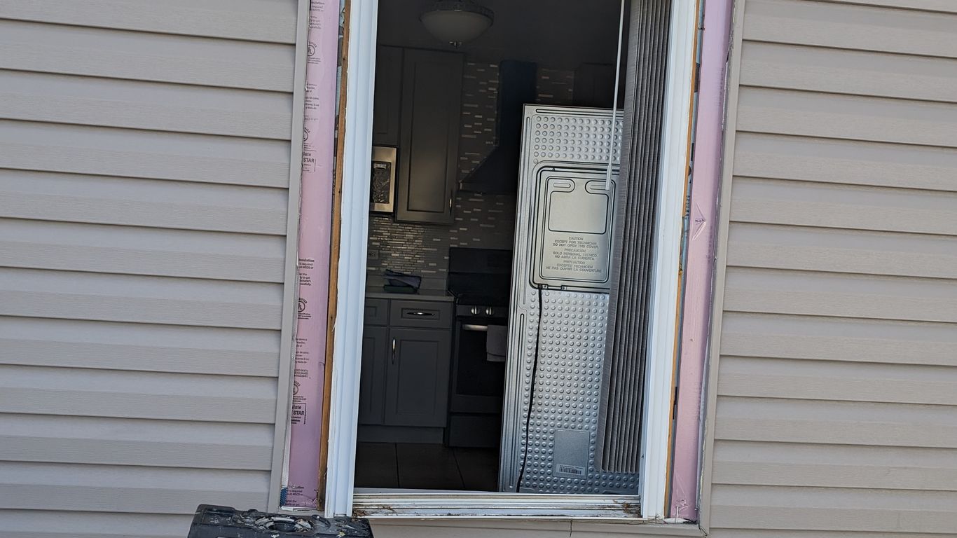 Window replacement in progress with insulation and a ladder.