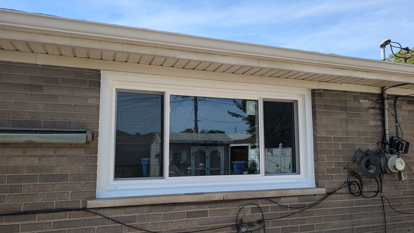 A new white sliding window is installed on a brick wall.